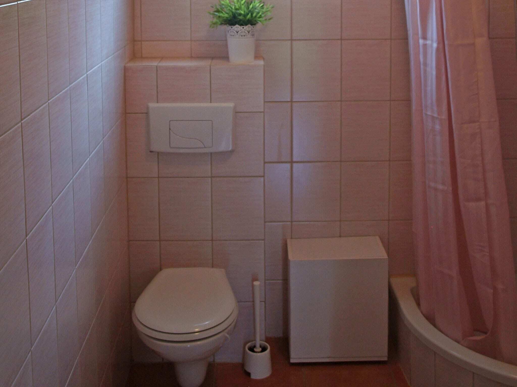 Un baño pequeño con azulejos, que incluye un inodoro, un bidé, un cepillo para el inodoro y una cortina de ducha.