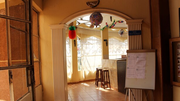 Una habitación con una pizarra, un letrero de bar y una ventana con cortinas.