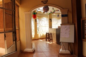 Una habitación con una pizarra, un letrero de bar y una ventana con cortinas.