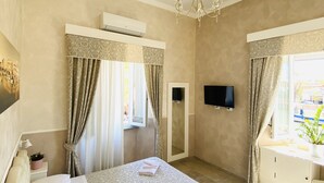 A hotel room with a bed, a TV, an air conditioner, and a window with curtains. - Domus Valadier Guesthouse (Fiumicino)