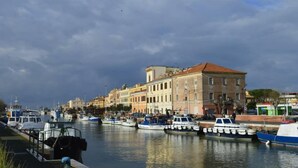 A marina with boats docked along a waterfront, buildings in the background, and a cloudy sky. - Domus Valadier Guesthouse (Fiumicino)