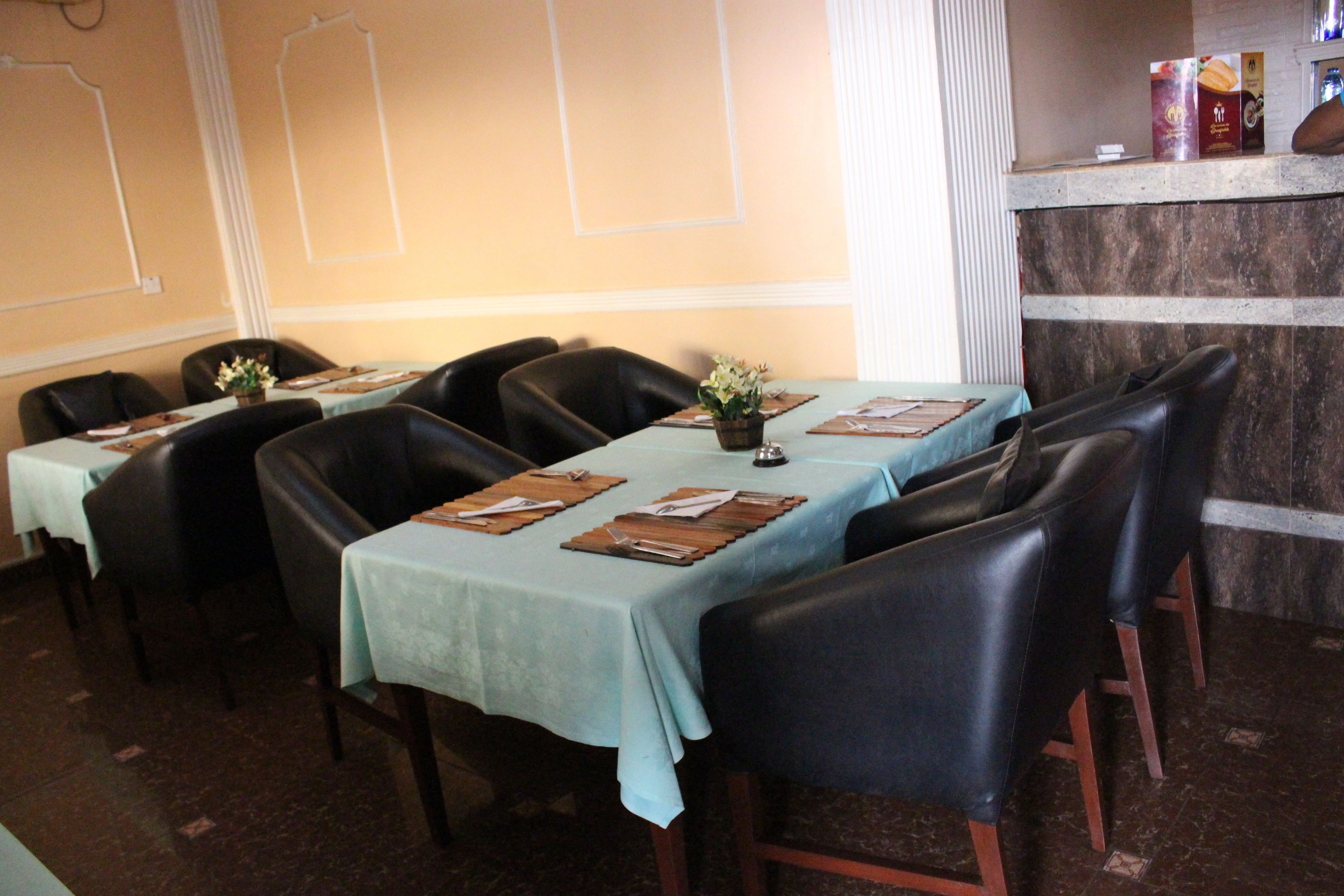 A restaurant with tables set for dining, chairs, and a counter with menu items.