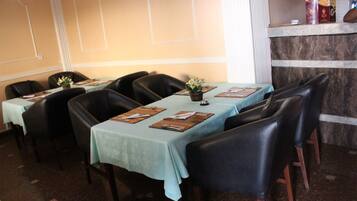 A restaurant with tables set for dining, chairs, and a counter with menu items.