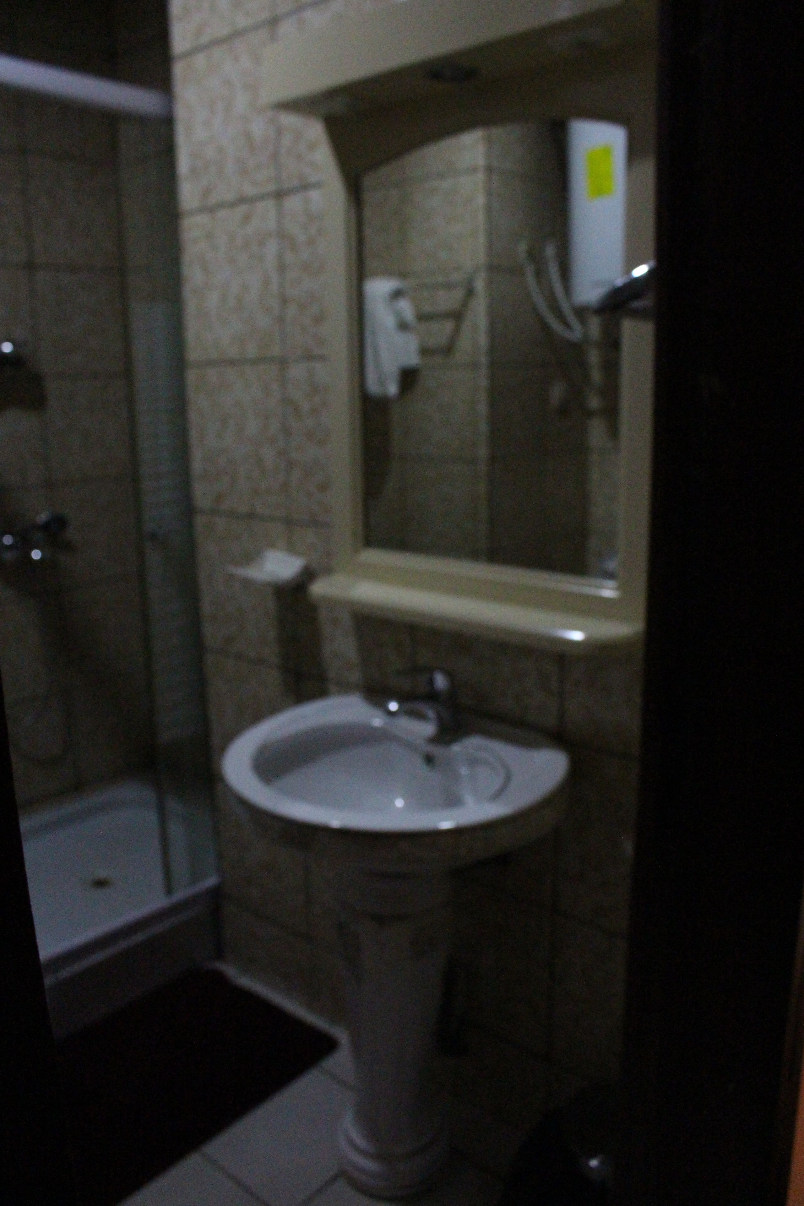 Un baño con lavabo pedestal, espejo y cabina de ducha.