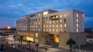 A modern hotel with a flat facade, multiple balconies, and a well-lit entrance. - Fiesta Inn Silao Puerto Interior (Silao)