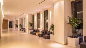 A modern hotel lobby with a long reception area, seating, and potted plants. - Fiesta Inn Silao Puerto Interior (Silao)