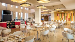 A spacious dining area with modern pendant lighting, a central bar, and a vibrant wall art display. - Fiesta Inn Silao Puerto Interior (Silao)