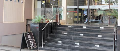 The exterior of Howard Johnson Hotel with a staircase leading to the entrance, a signboard with the hotel's name, and a menu stand outside.