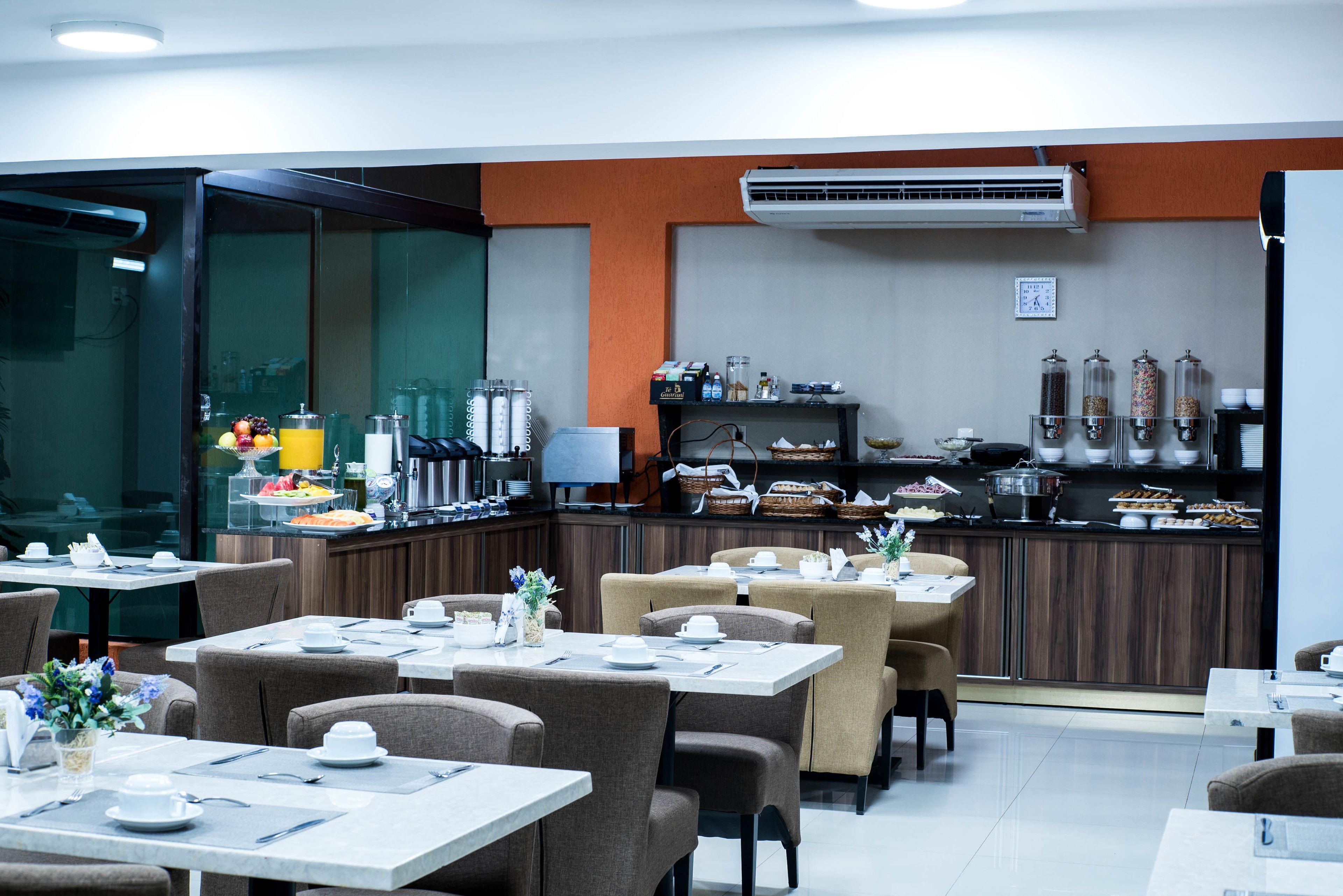A restaurant with tables set for dining, a kitchen area, and a buffet with various food items.