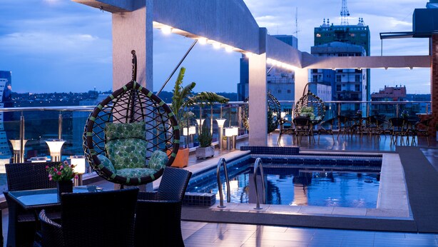 A rooftop pool area with lounge chairs, a swimming pool, and city views.