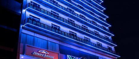 A hotel with multiple floors, illuminated by blue lights, and featuring signs for Howard Johnson and Janklow Bros.