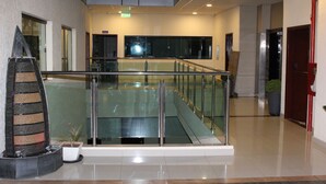A modern indoor area with a glass railing, a water feature, and a staircase.
