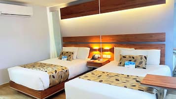 A hotel room with two beds, a wooden headboard, bedside lamps, a nightstand, and a small table.
