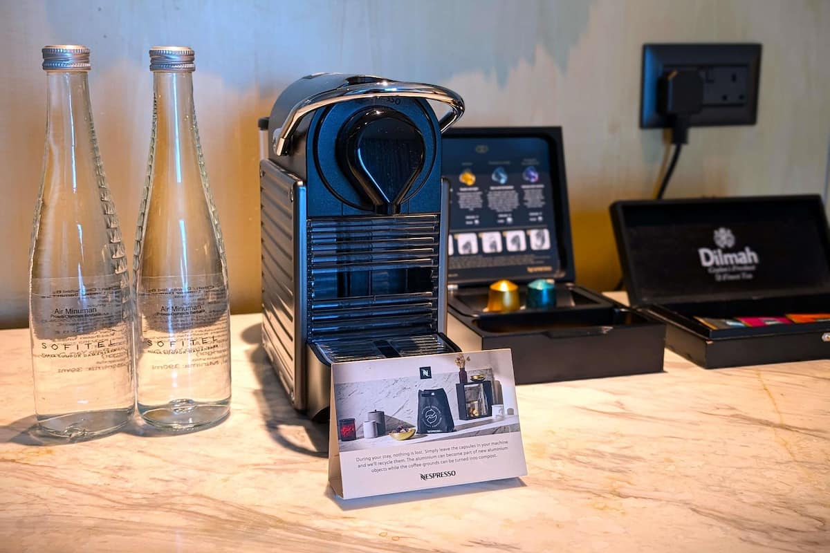 Une machine à café, deux bouteilles d’eau, une machine Nespresso et un panneau d’information sur le recyclage.