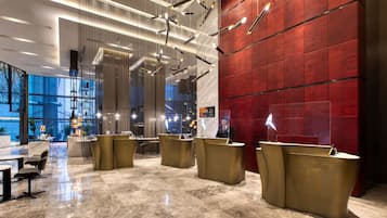 A modern lobby with a reception desk, seating area, and a large red wall.