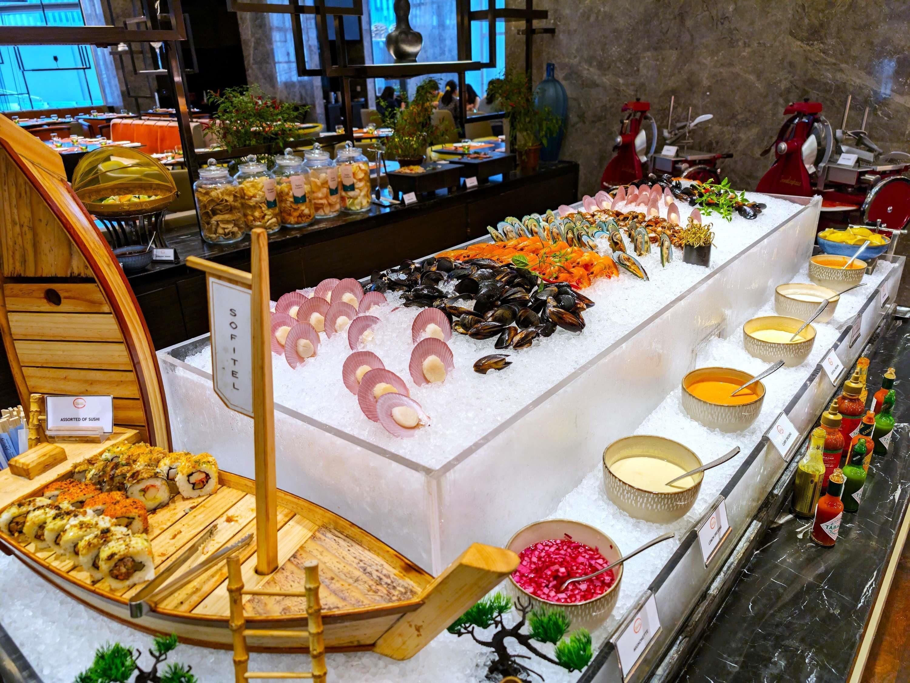 Un bufé con mariscos, sushi y salsas.