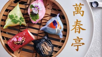 Una cesta de bambú para cocinar al vapor con varios dumplings en un plato.
