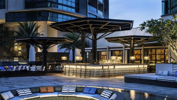 A modern outdoor bar area with seating and a heated outdoor pool.