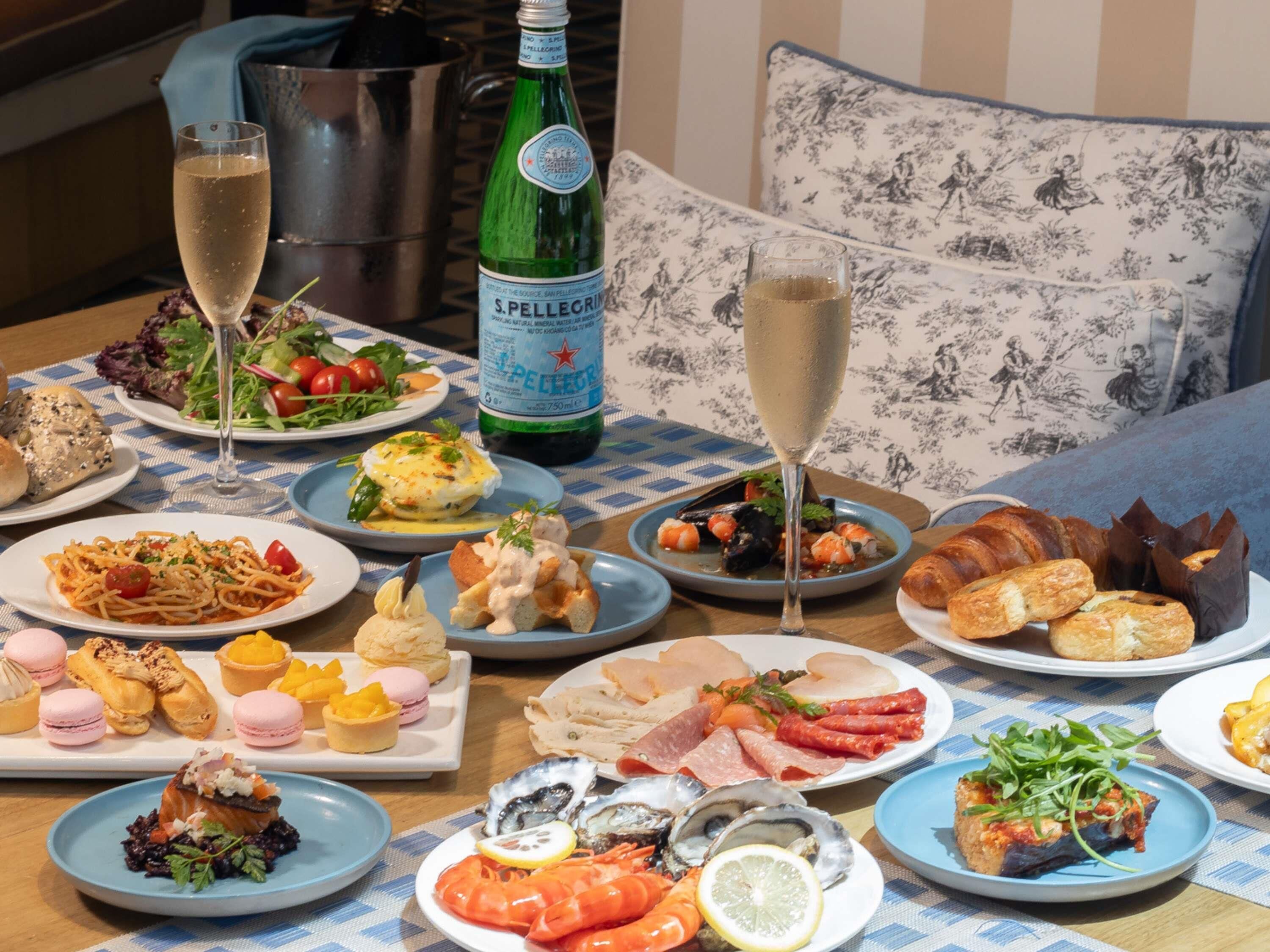 A table set with various dishes, a bottle of S.Pellegrino water, and glasses of champagne.