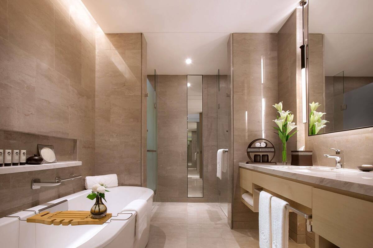 A modern bathroom with a freestanding bathtub, a large mirror, and a vanity with a towel rack.