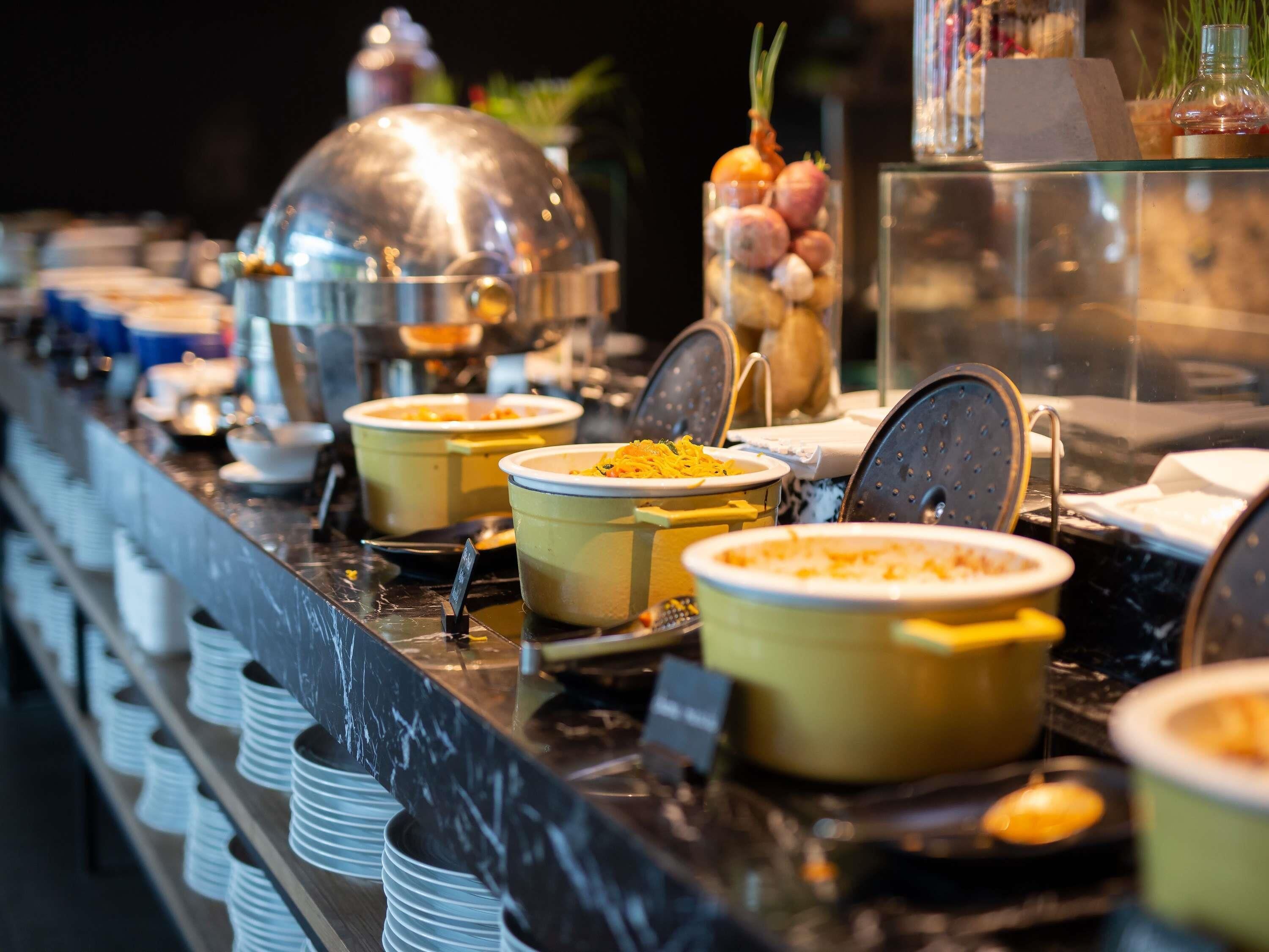 A buffet line with various food containers and utensils.