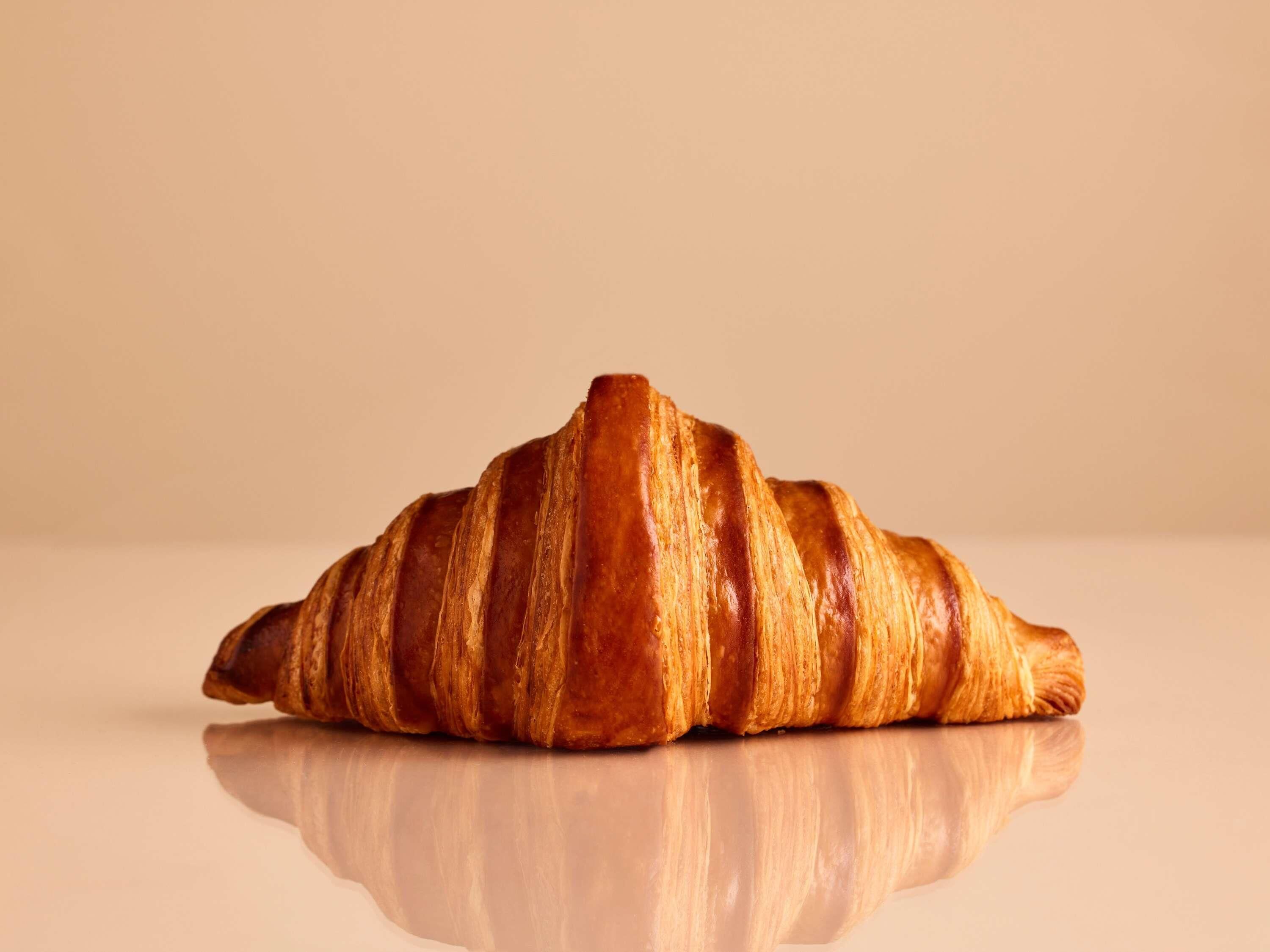 A single croissant on a reflective surface.