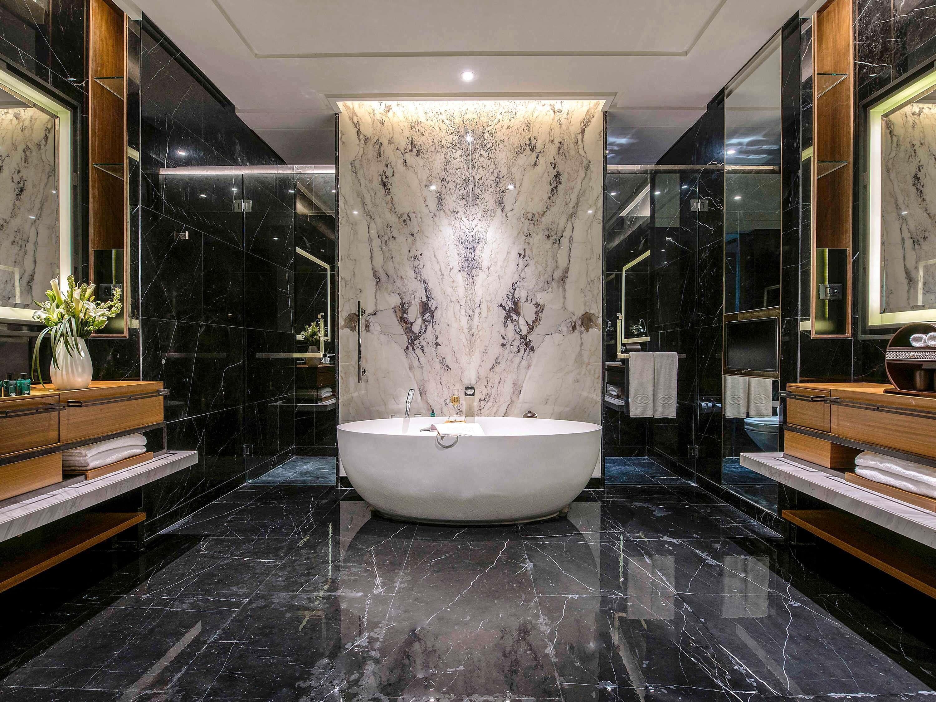 Ein modernes Badezimmer mit einer freistehenden Badewanne, Marmorwänden und Holzschränken.