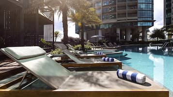 Un área junto a la piscina con sillones reclinables.