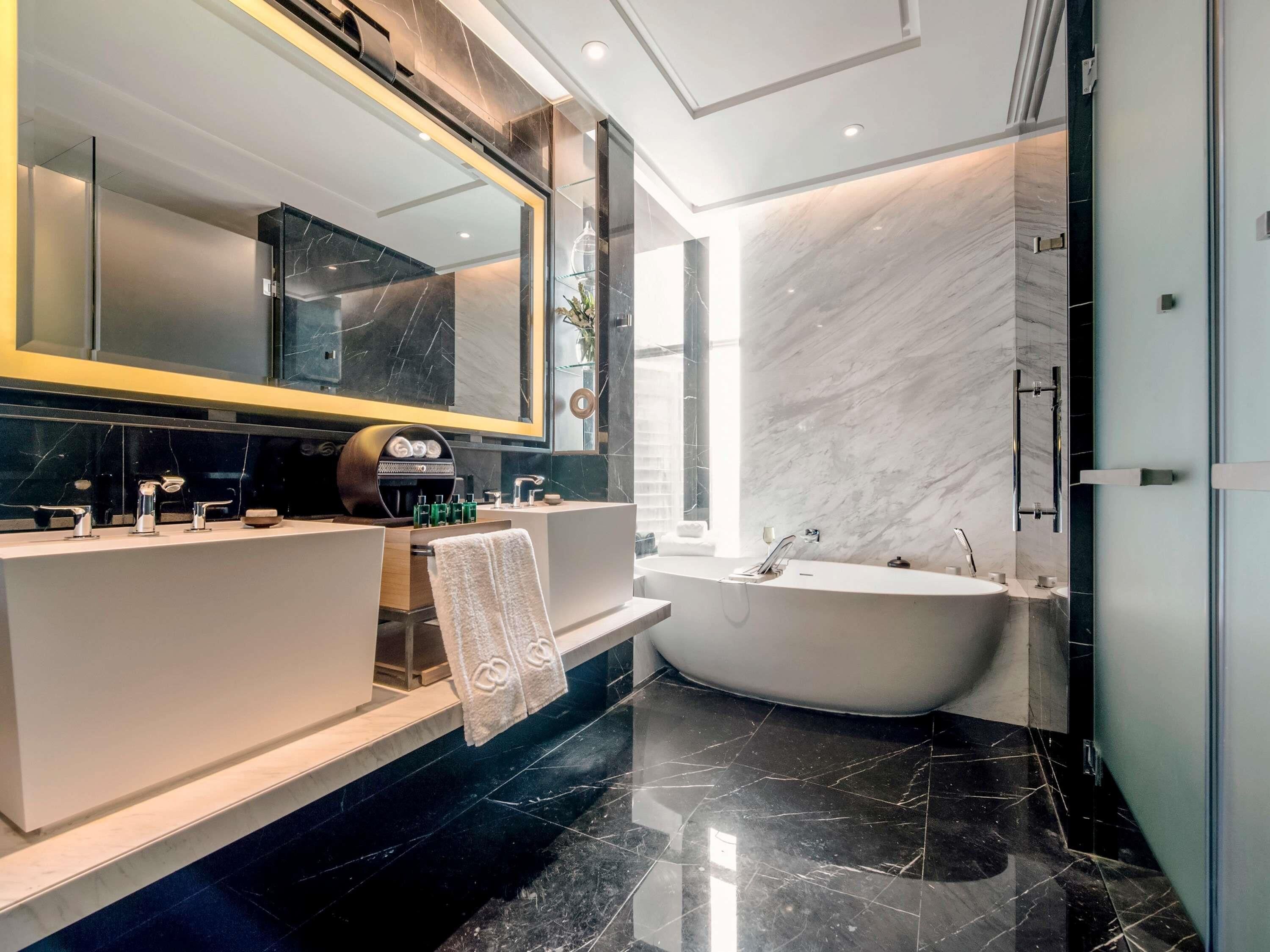 A modern bathroom with a vanity, a large mirror, a bathtub, and a glass shower enclosure.