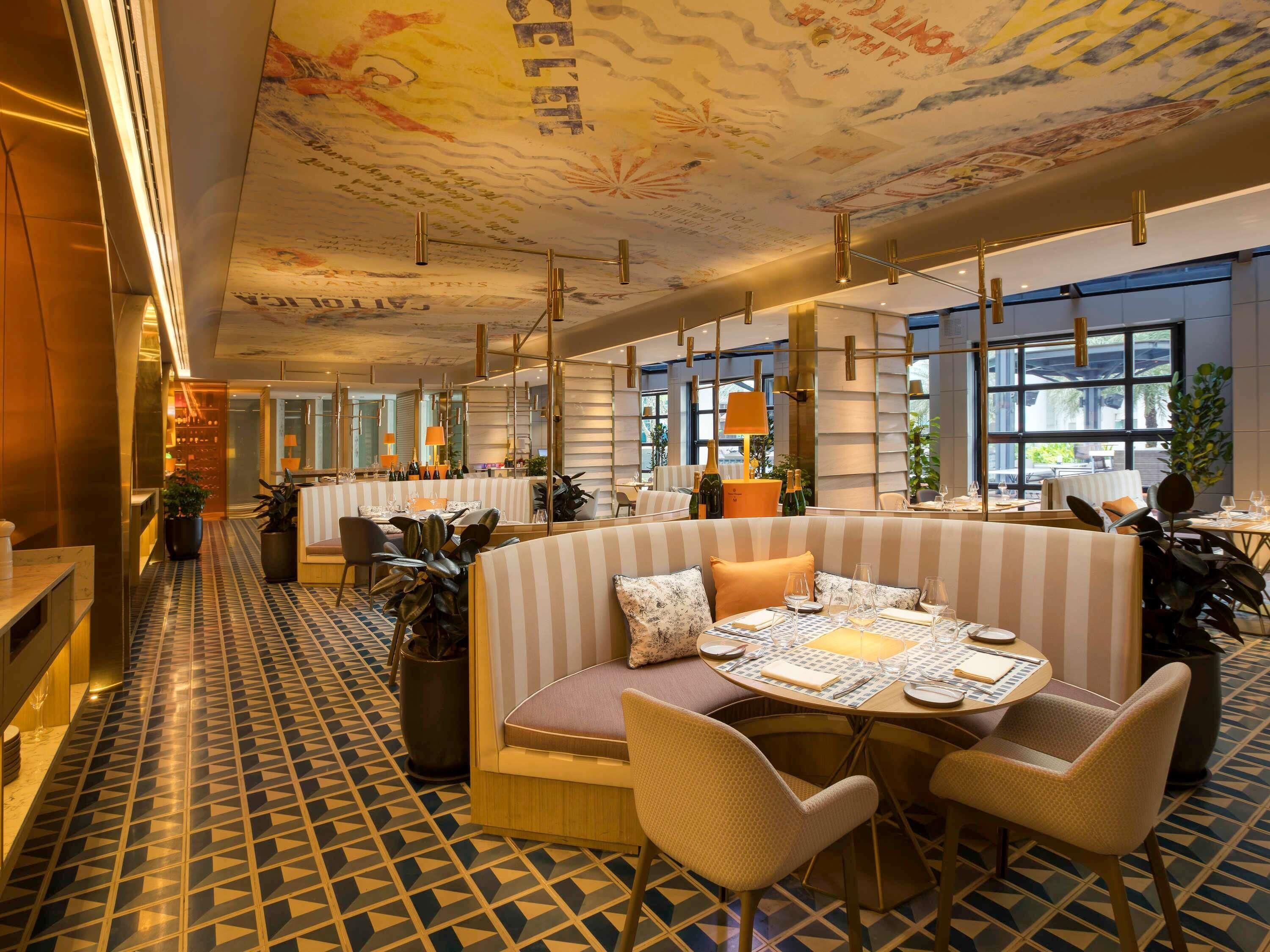 A modern restaurant with striped booths, a patterned floor, and a ceiling with artistic designs.
