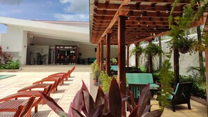 An outdoor patio area with wooden benches, a covered seating area, and potted plants. - Hotel Agualcas (Managua)