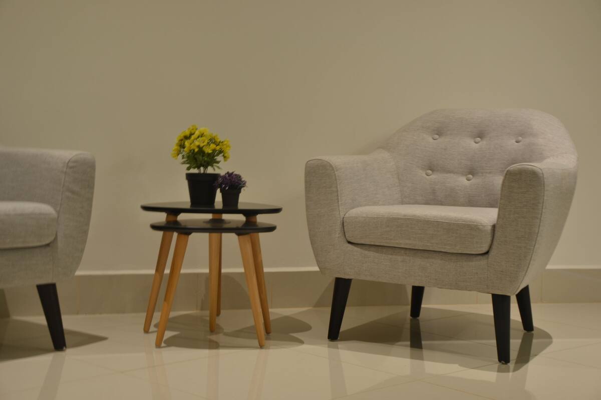 A modern room with a grey armchair and a small table with a potted plant.