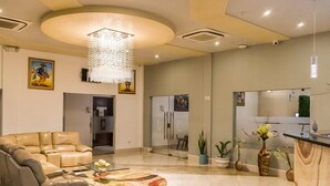 A spacious living area with a leather sofa, a glass coffee table, and a chandelier. - Hotel Agualcas (Managua)