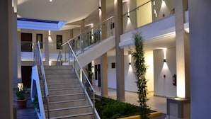 A multi-level interior with a central staircase, glass railings, and potted plants. - Hotel Agualcas (Managua)