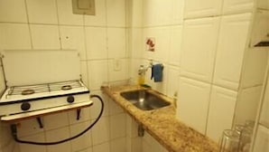 A small kitchen with white tiles, a gas stove, a sink, and a countertop. - GoHouse Copacabana 302 C (Rio de Janeiro)