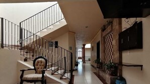 Un hall spacieux avec un escalier, une chaise et un motif à carreaux sur le mur.