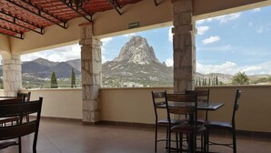 Une terrasse avec des piliers en pierre, un sol carrelé et une vue sur une montagne.