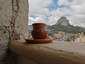 A terracotta pot on a ledge with a view of a mountain and a town in the background.