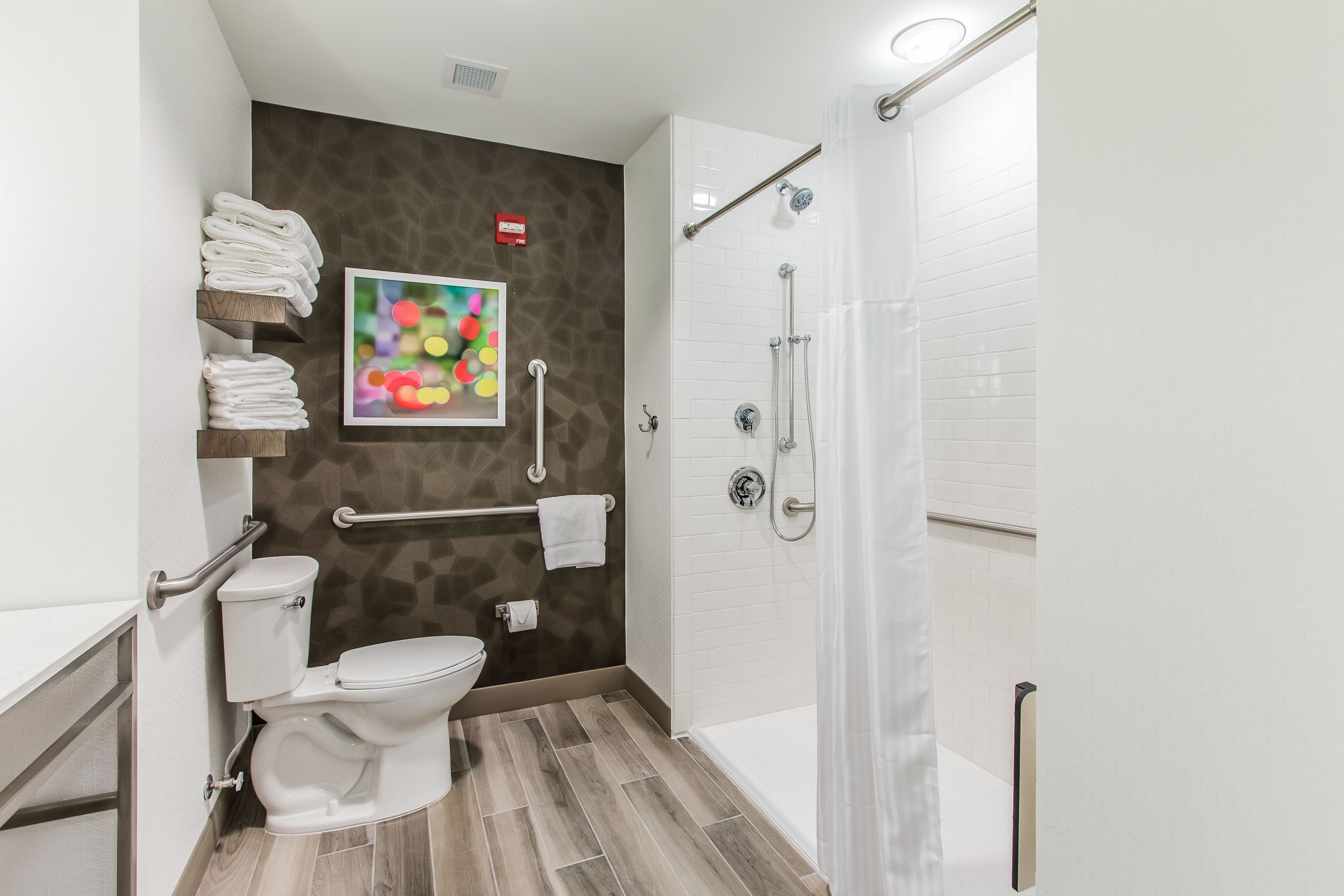 Une salle de bain moderne équipée d’une douche, de toilettes et de barres d’appui.