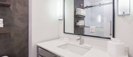 Une salle de bain moderne avec un lavabo en marbre blanc, un grand miroir et une cabine de douche en verre.