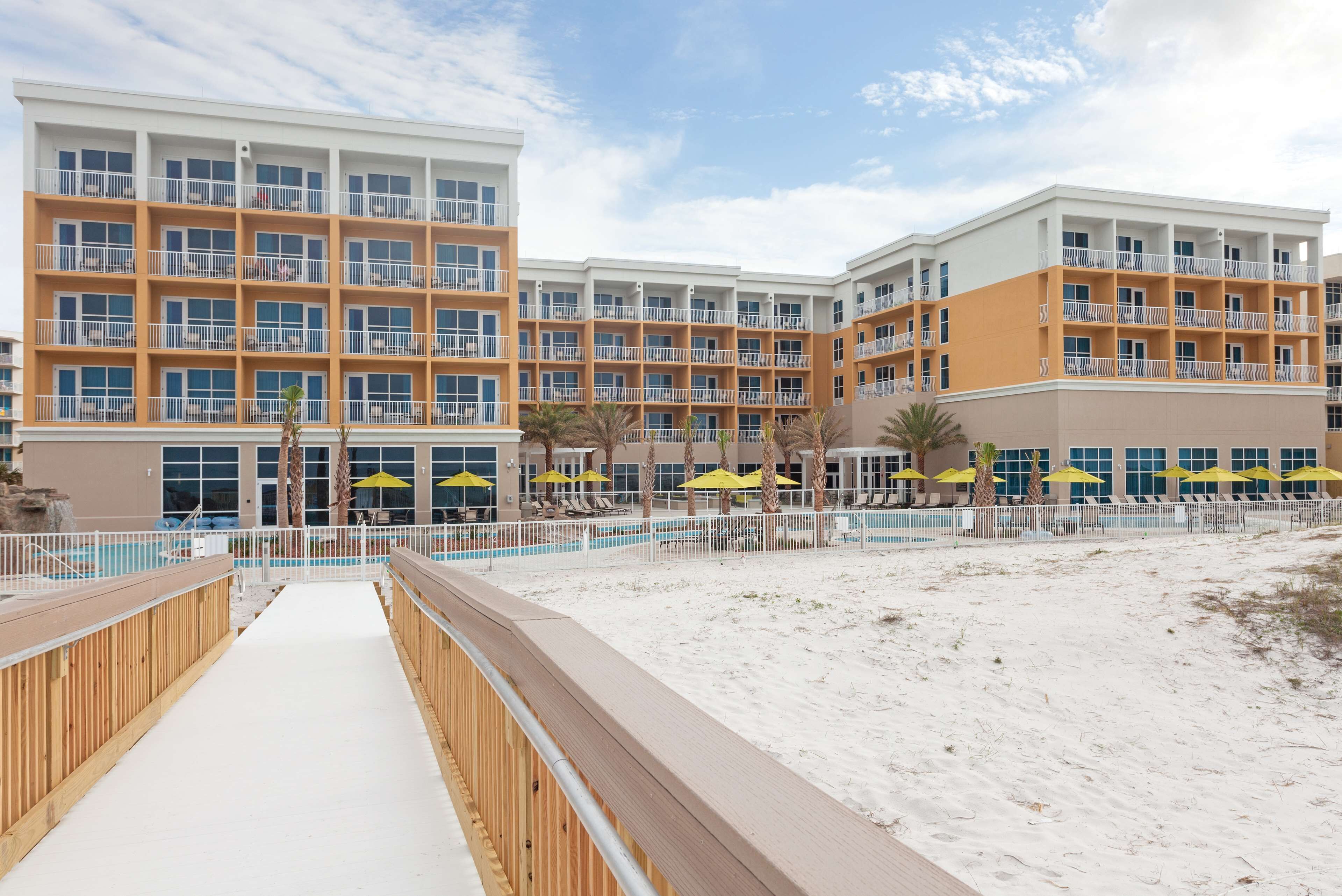 Un hôtel à plusieurs étages doté de balcons, d’un espace piscine et d’un accès à la plage.