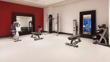 A gym with various exercise equipment, including treadmills, weight machines, and a bench.