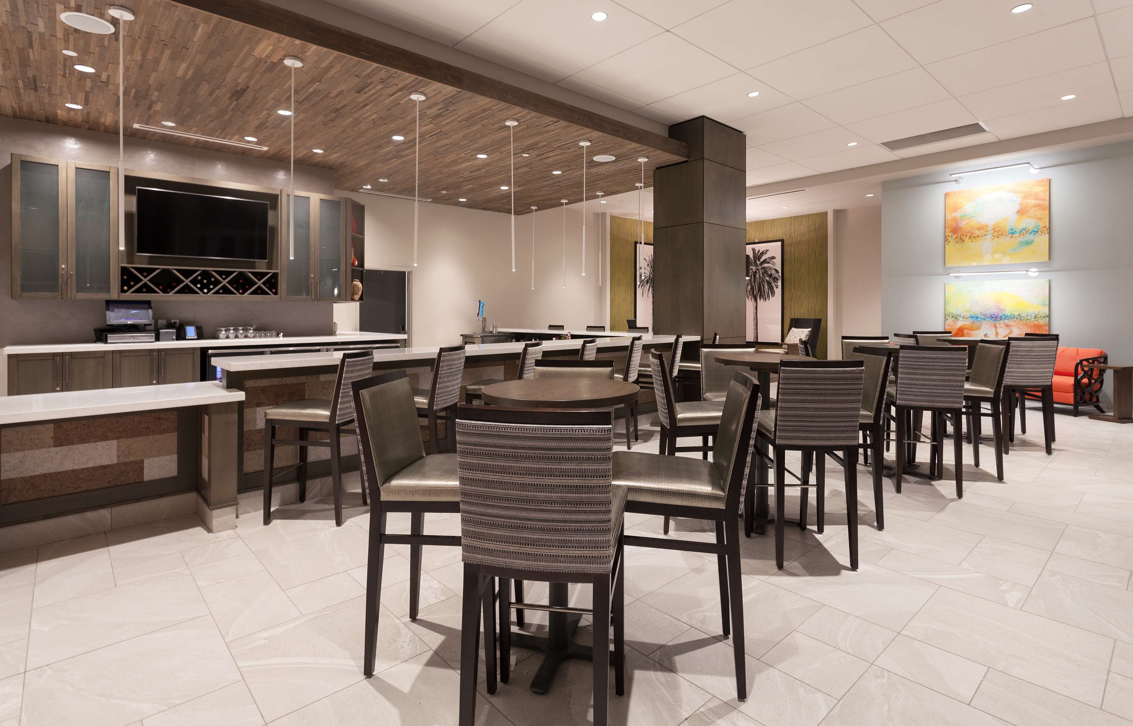 Un espace de restauration moderne doté d’un bar central, de plusieurs tables et de chaises.
