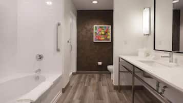 A modern bathroom with a walk-in shower, a large mirror, and a wooden floor.