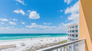 A beach view from a balcony overlooking a sandy beach with a clear blue sky.