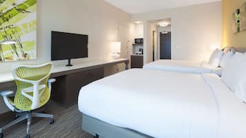 A hotel room with a bed, a desk with a chair, a TV, and a painting on the wall.