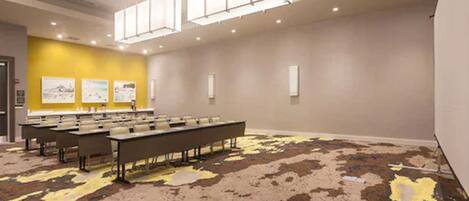 A conference room with a long table, chairs, and a yellow accent wall.