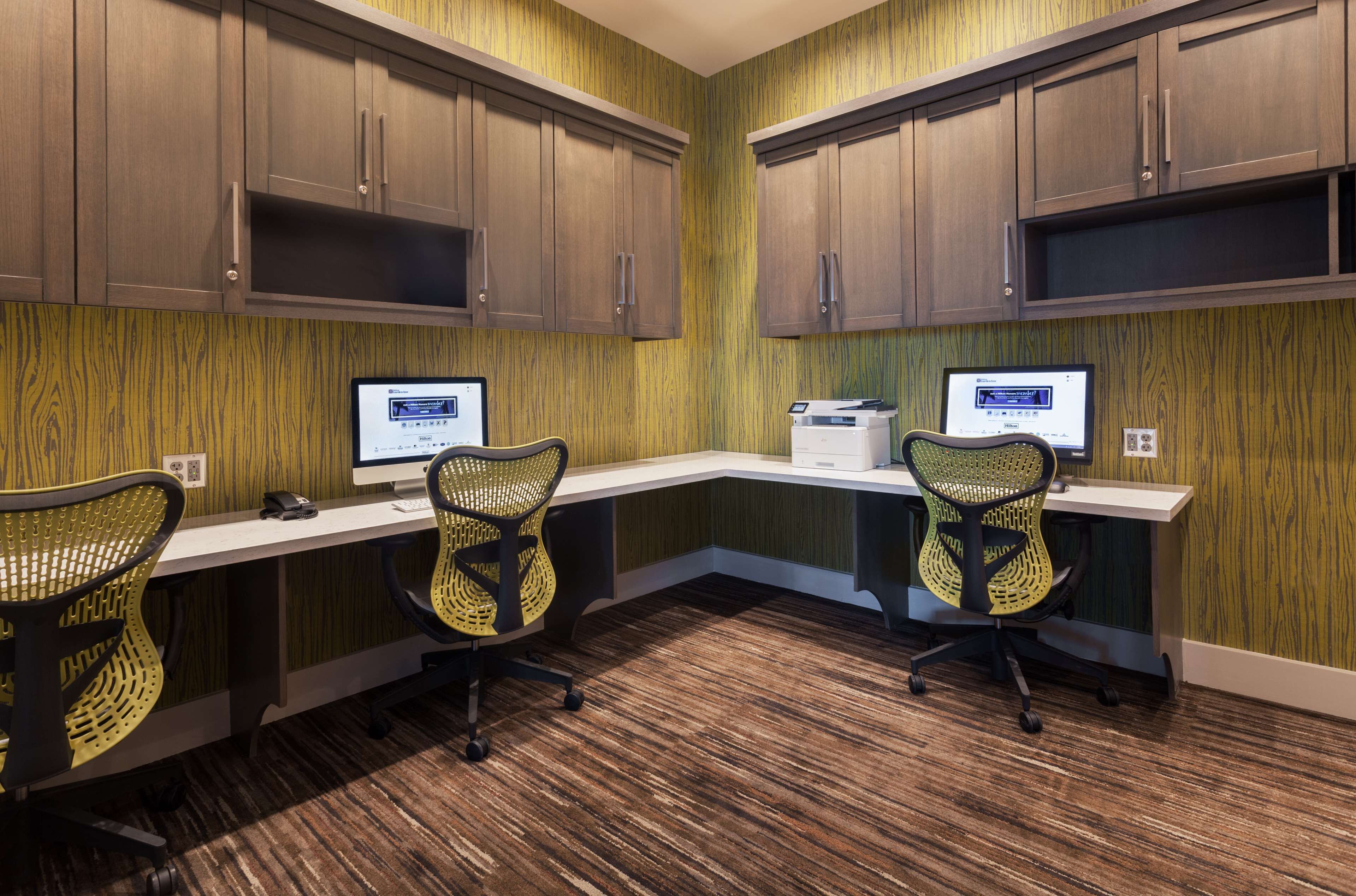 A conference room with two desks, two chairs, and wooden cabinets.
