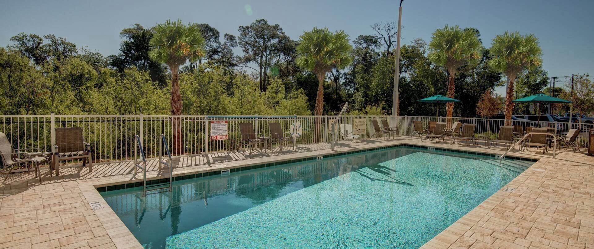 Una piscina al aire libre, sombrillas, sillones reclinables de piscina