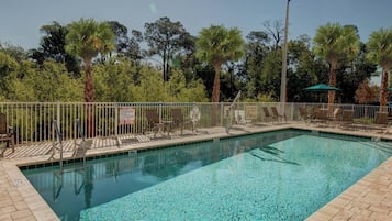 Una piscina al aire libre, sombrillas, sillones reclinables de piscina